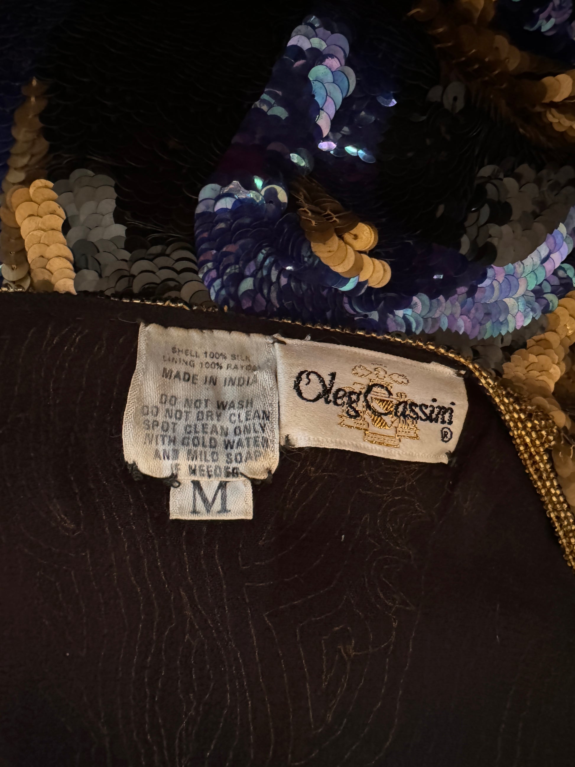 Close up view of Oleg Cassini label. This top is made in India. The shell of the top is 100% silk. The lining is 100% rayon. Size Medium. Care instructions, Hand wash cold. Do not dry clean.