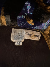 Cargar imagen en el visor de la galería, Close up view of Oleg Cassini label. This top is made in India. The shell of the top is 100% silk. The lining is 100% rayon. Size Medium. Care instructions, Hand wash cold. Do not dry clean.
