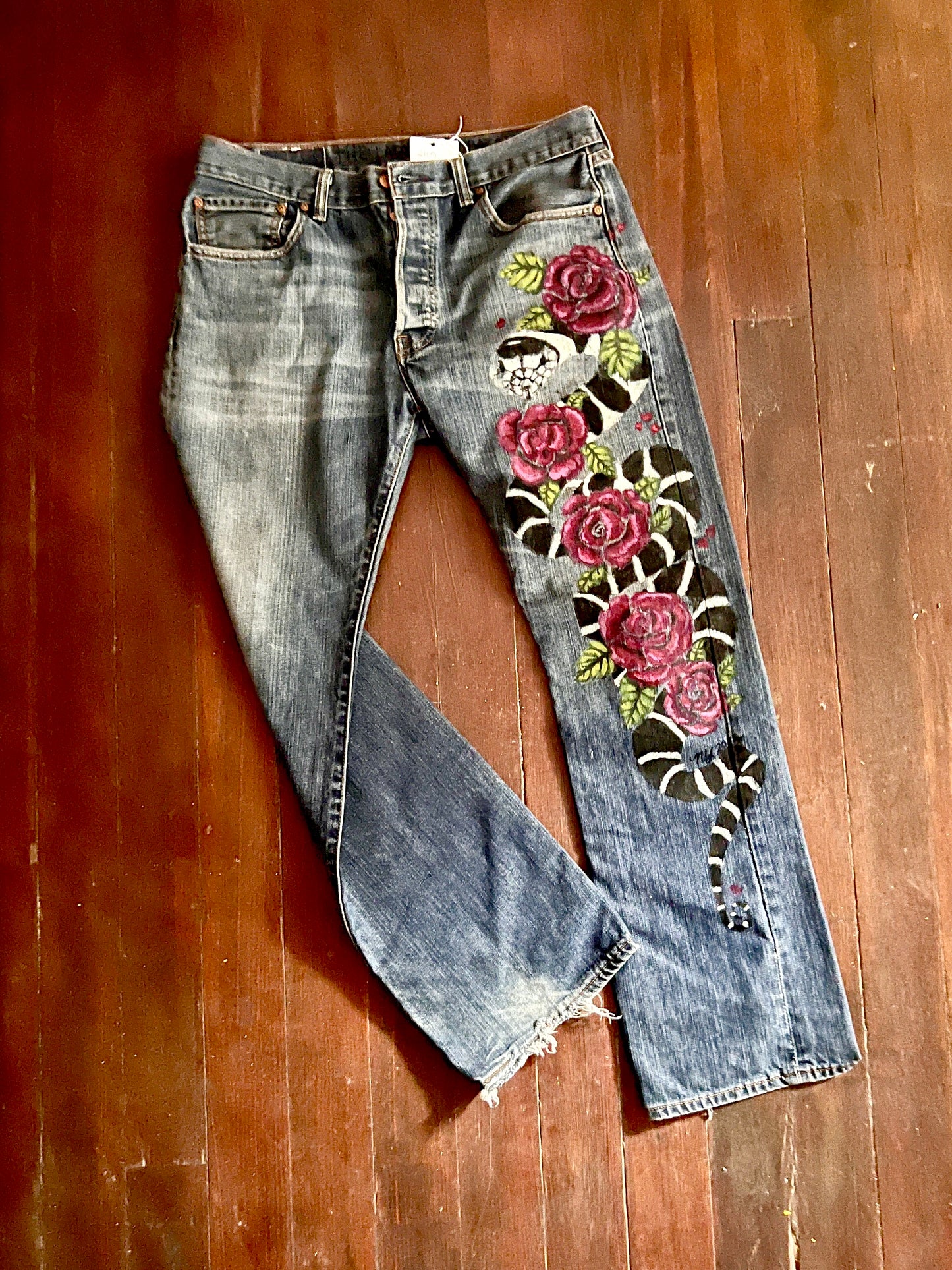 Full view of King Snake in Roses jeans with distressed hem visible. 