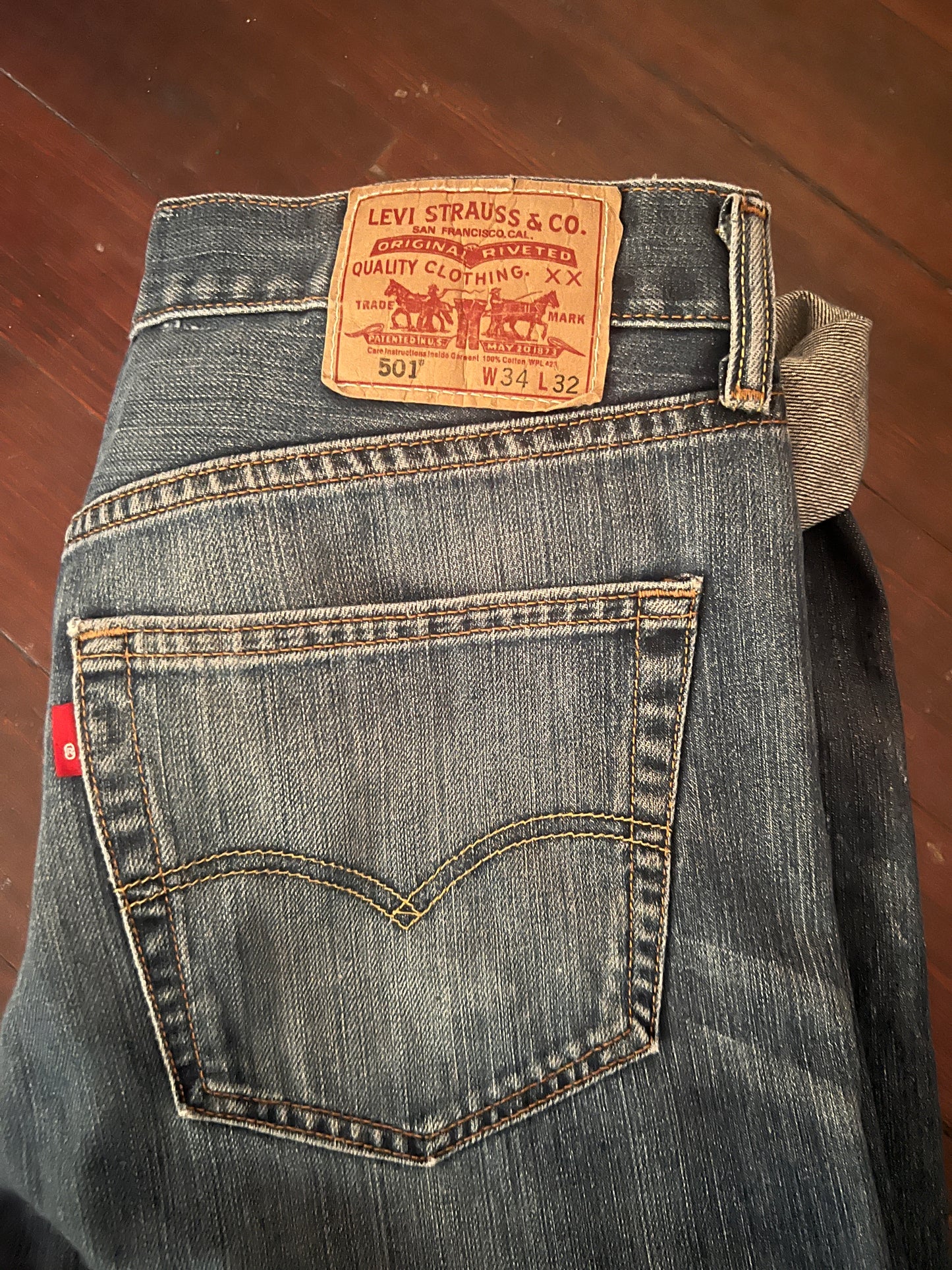 View of back pocket and Levi's 501 label. The jeans are pre-owned in good condition with distress hems.