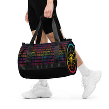Load image into Gallery viewer, Freedom Go! Duffel Bag being shown as a workout bag, it also works as a weekender bag too! The polychromatic atom emblem is screen printed to fill the side panel. The bottom panel is shown in solid black.

